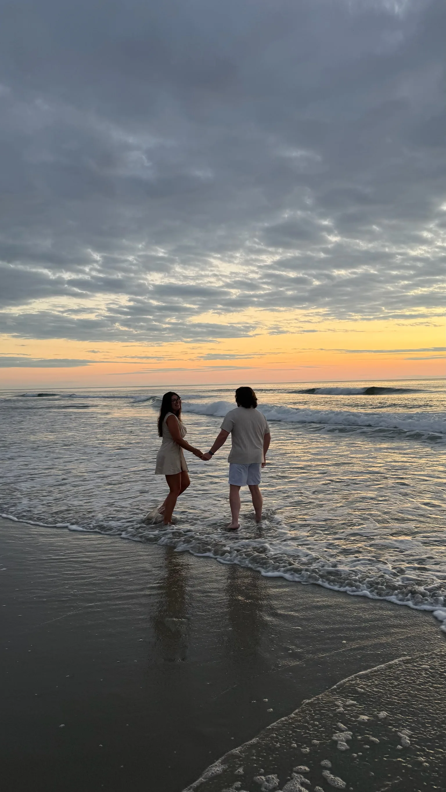Isabella and Johnny holding hands at sunset on the beach